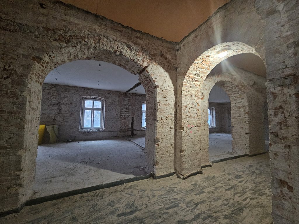Wnętrze budynku podczas budowy. Ceglane ściany ze zdjętym tynkiem.